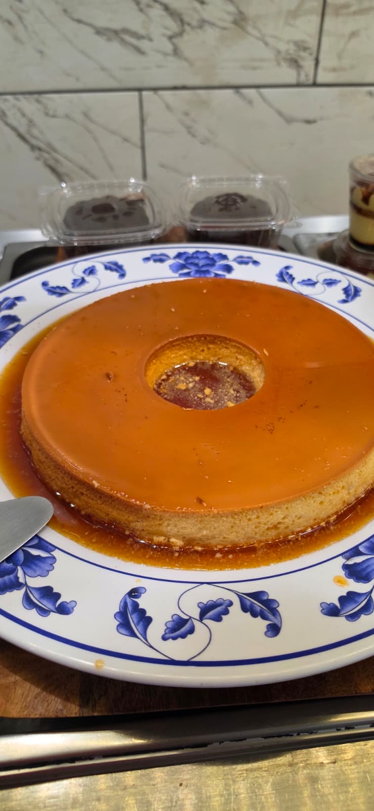 Whole Brazilian milk pudding (pudim) glazed in caramel on a blue-and-white plate