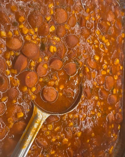 Tray of sliced sausage in tomato sauce with corn
